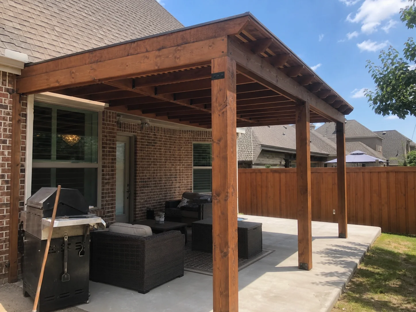 Wood pergola behind a brick Dallas home