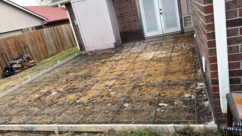 Graded backyard patio base beside a Dallas brick house
